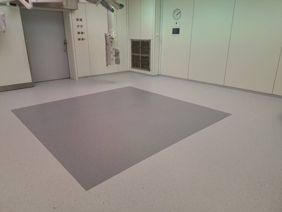 Une salle d'opération vide avec un grand tapis carré sur le sol.