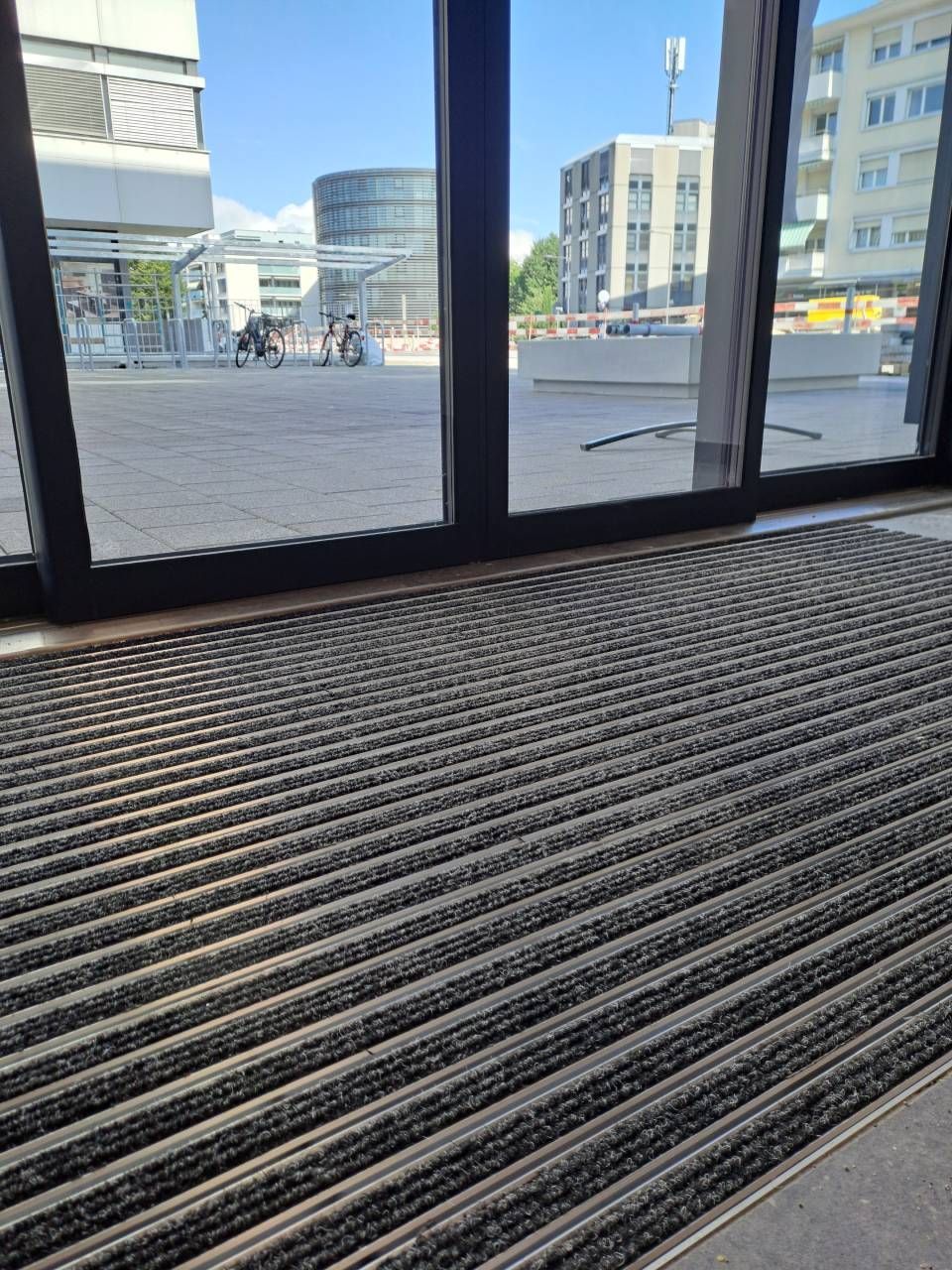 Un tapis noir est posé sur le sol devant une porte coulissante en verre.