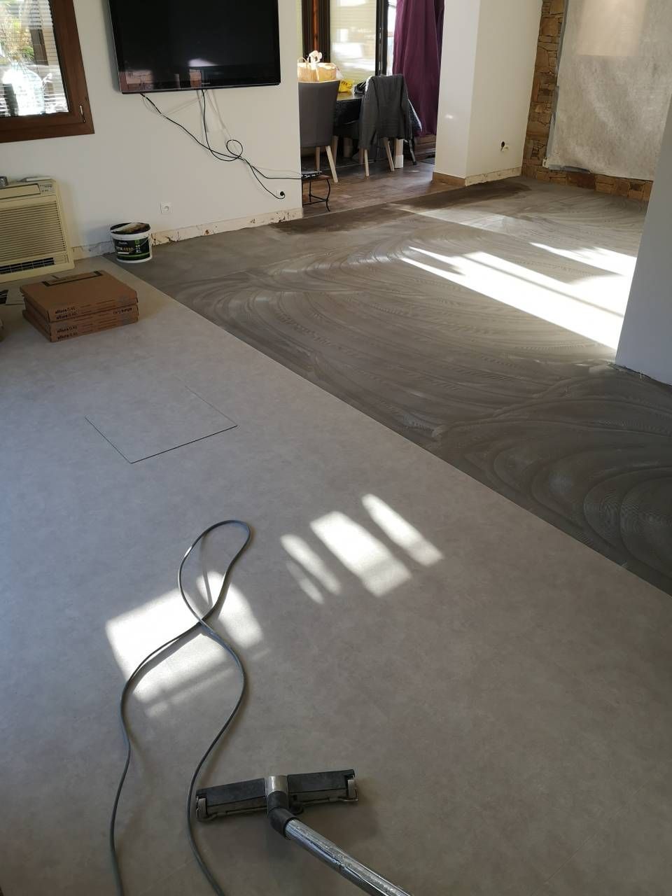 Une pièce avec un sol en béton et une télévision au mur.