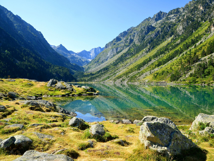 Lac de montagne aux eaux vertes et limpides, aux rives rocheuses et aux sommets boisés.