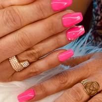 Gros plan sur des mains aux ongles manucurés rose vif et aux bagues en or.