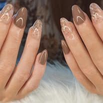 Des mains aux ongles nude en amande ornés de motifs floraux reposent sur une surface en fourrure blanche.