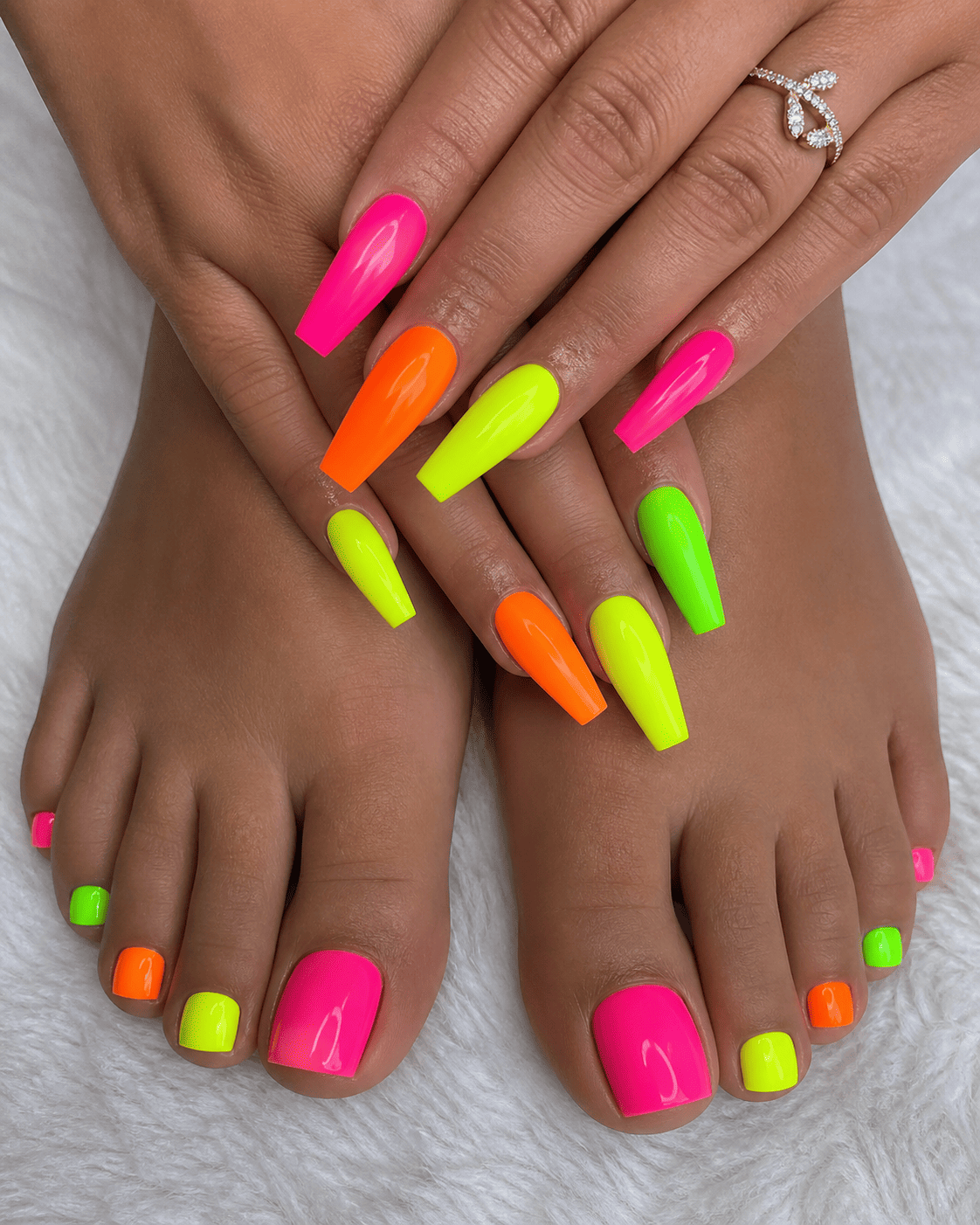 Mains et pieds aux longs ongles rose fluo, orange et vert.