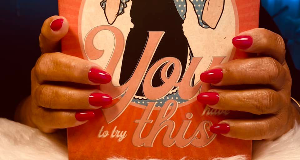 Des mains avec vernis rouge sur les ongles tenant une tasse.