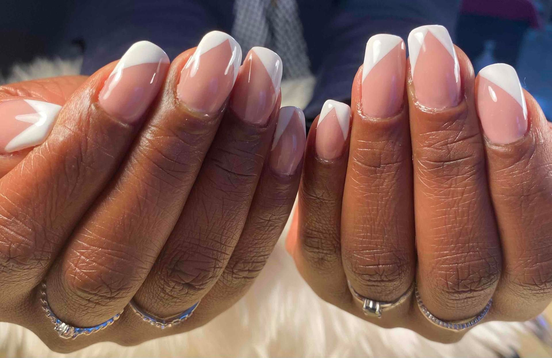 Des mains avec une French manucure nude brillante.