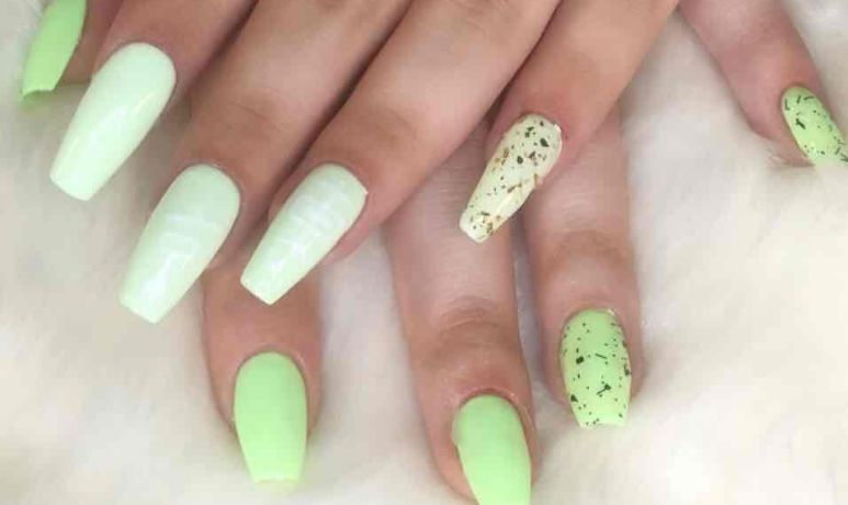 Mains aux ongles longs, manucurés, vert pastel et vert fluo moucheté, sur fond de fourrure blanche.