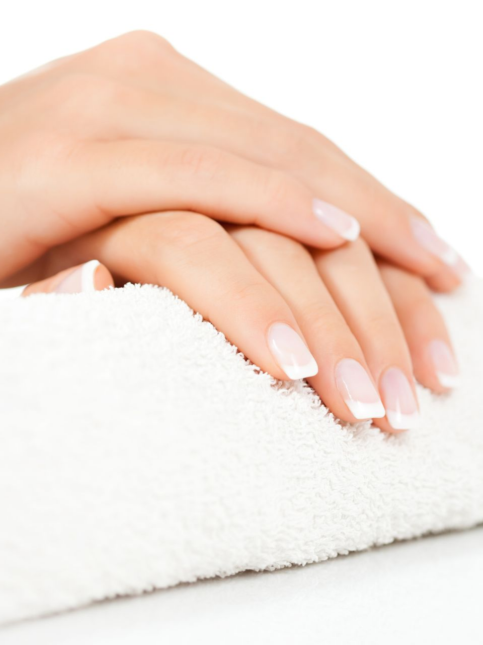 Des mains aux ongles blancs manucurés reposent sur une surface blanche texturée.