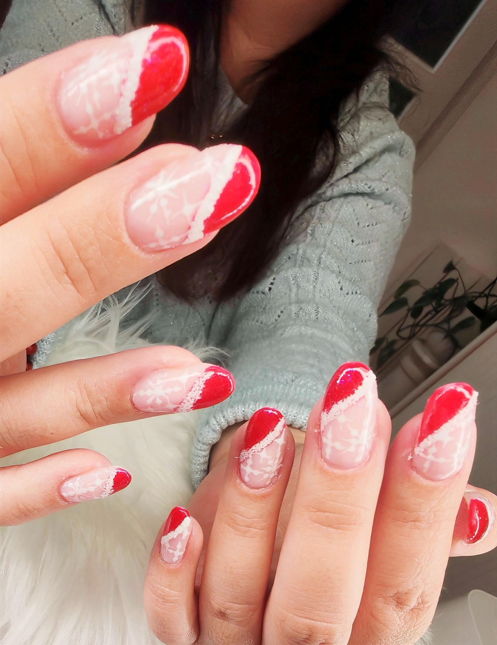 Des mains aux ongles vernis à la française, rouges et blancs, sont présentées devant un miroir.