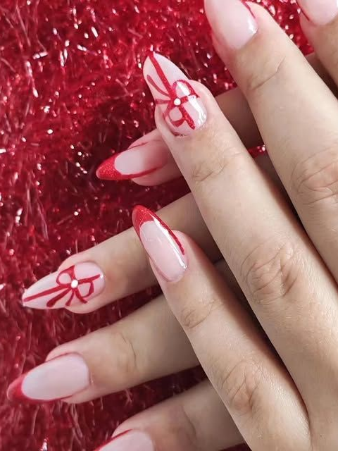 Mains avec un nail art nude et rouge sur un fond texturé scintillant rouge.