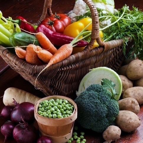 Panier de légumes et de fruits frais, comprenant des carottes, du brocoli, des petits pois, des pommes de terre, des tomates et des légumes à feuilles vertes.