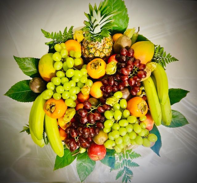 Composition de fruits colorés avec raisins, bananes, ananas, oranges et feuillages sur fond blanc