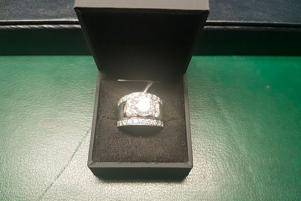 Un anillo de diamantes está en una caja negra sobre una mesa verde.