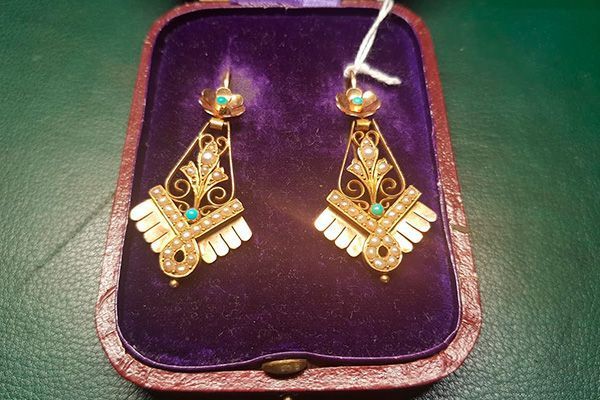 Un par de pendientes de oro en una caja morada.