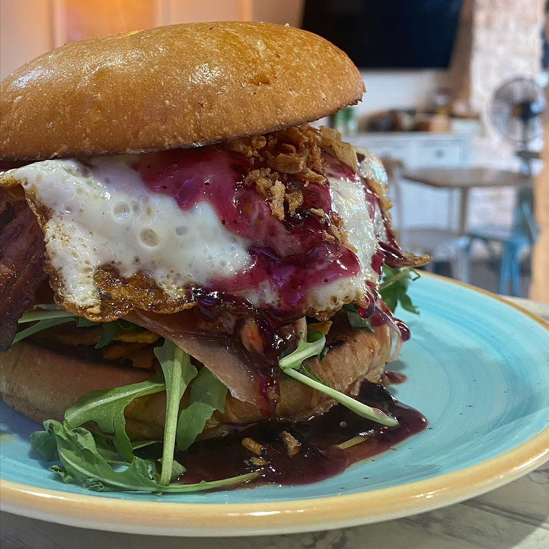 Un primer plano de una hamburguesa en un plato azul sobre una mesa.