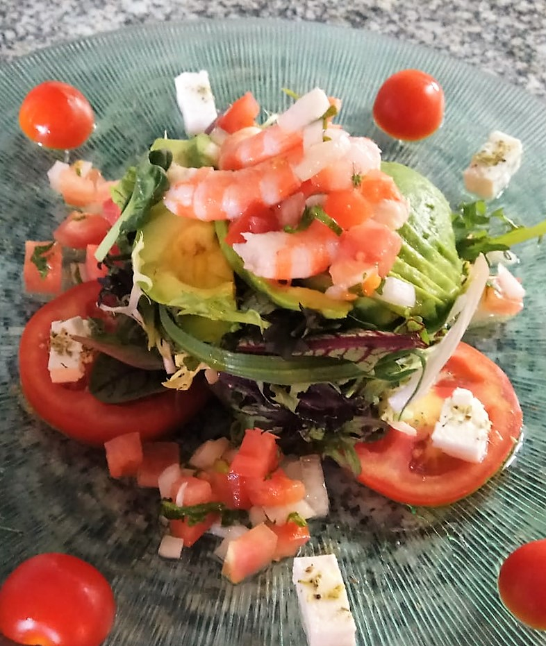 Una ensalada con camarones y tomates en un plato.
