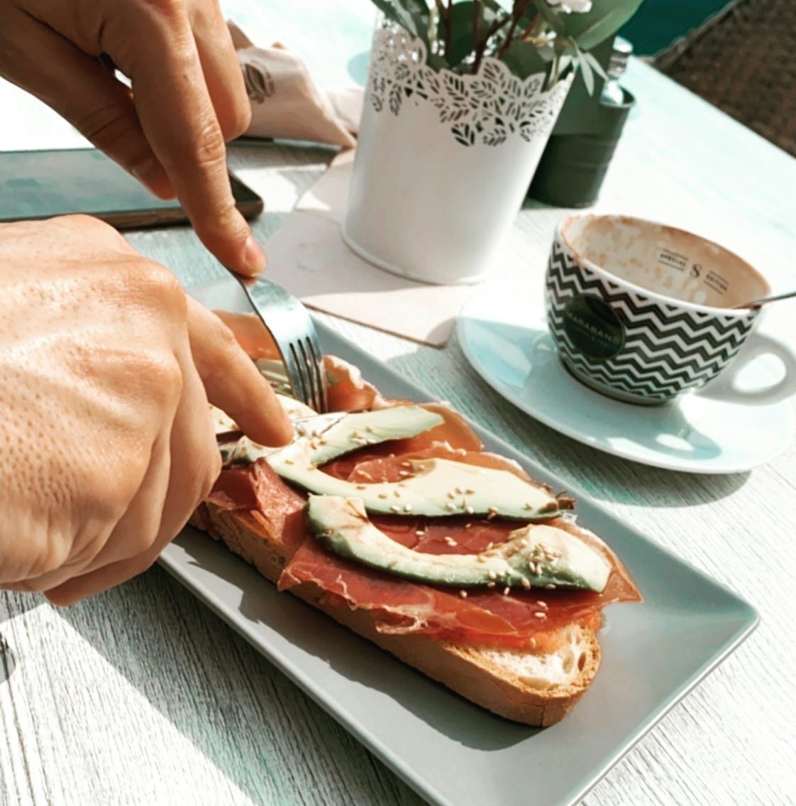 Una persona está cortando un sándwich con un tenedor en un plato.
