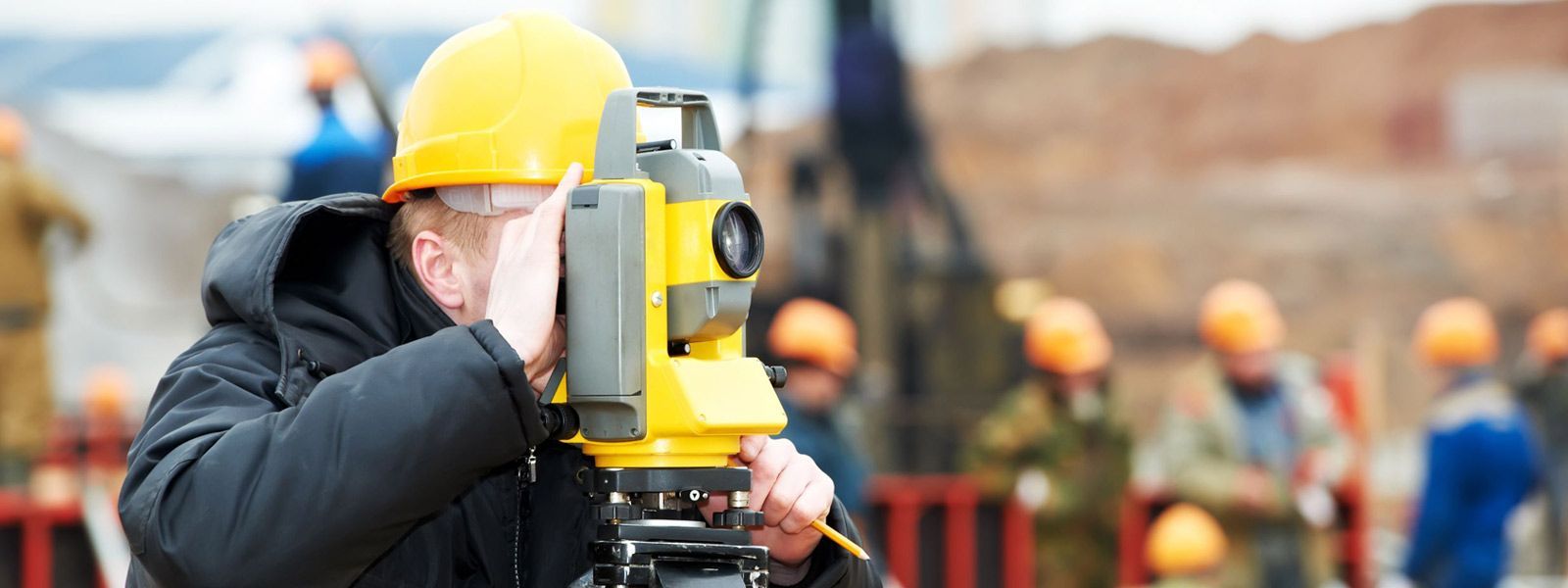 Un hombre con casco está utilizando un teodolito en un sitio de construcción.