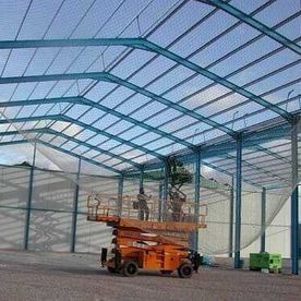 Un elevador de tijera se encuentra dentro de un gran edificio en construcción.