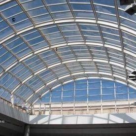 Un gran techo de cristal en un edificio con un cielo azul de fondo.