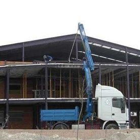 Un camión con una grúa acoplada está estacionado delante de un edificio en construcción.