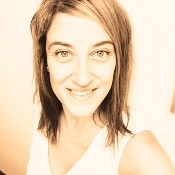 Mujer de piel clara, sonriente, vistiendo un top blanco, cabello castaño.