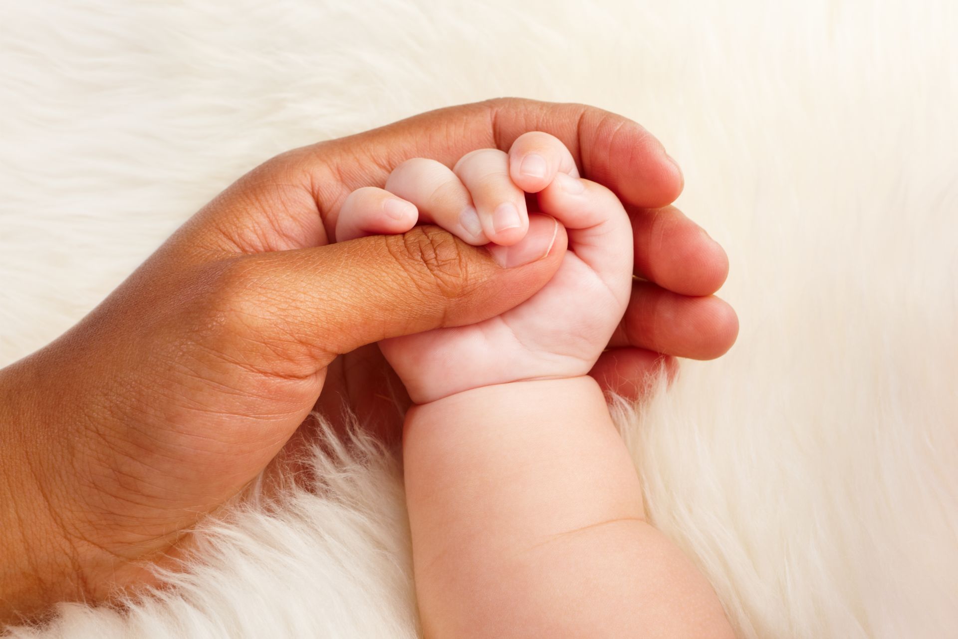 Une main de bébé qui serre le pouce de sa maman