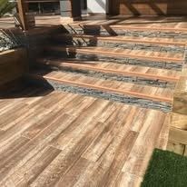 Terraza de madera con escalones de baldosas que conducen a un patio elevado al aire libre.