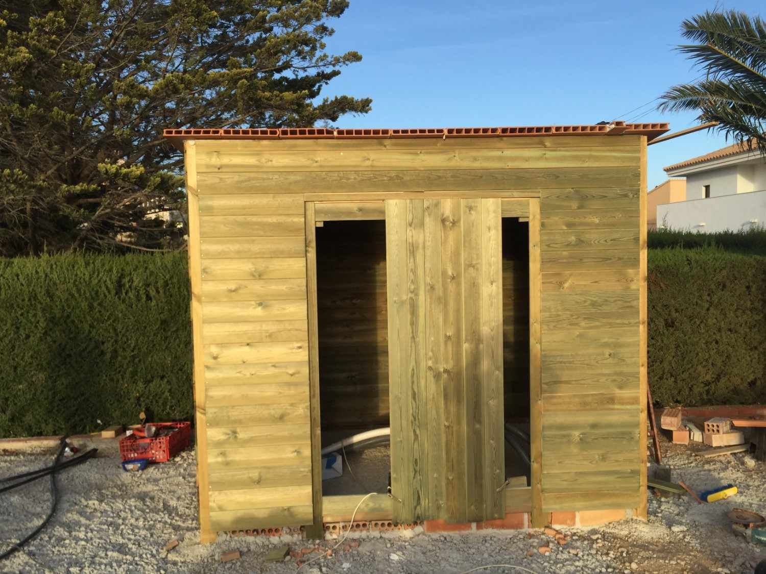 Pequeño cobertizo de madera sin terminar con una puerta abierta en un patio trasero.
