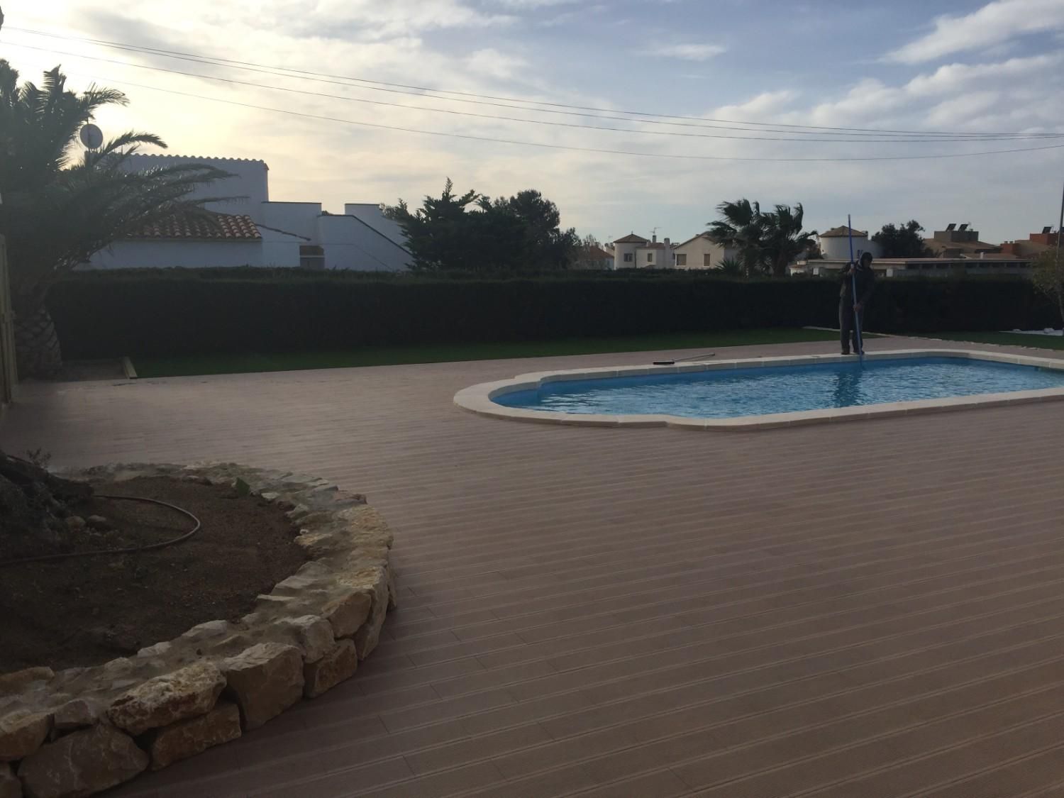 Patio trasero con una pequeña piscina redonda al atardecer, con una persona de pie junto al agua.