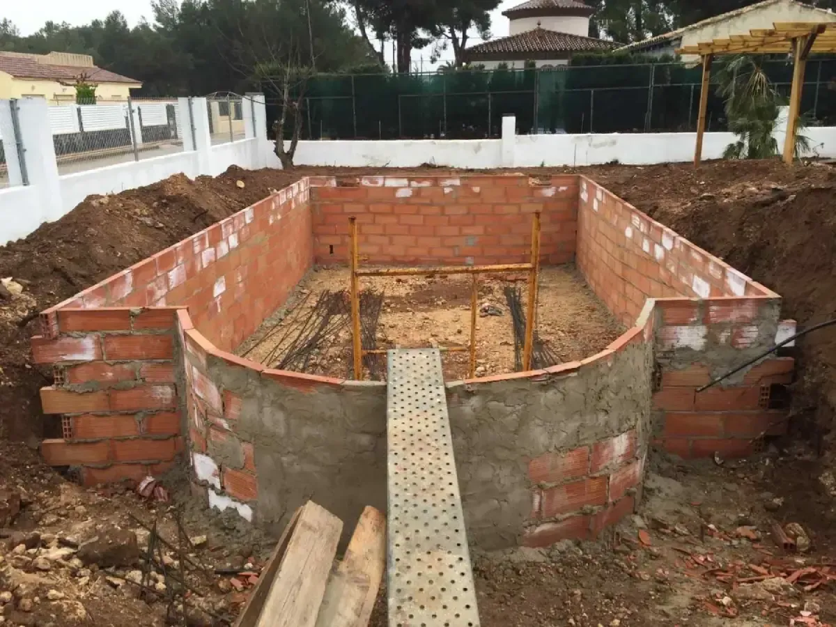 Piscina de ladrillo parcialmente construida o pequeña cuenca con paredes de hormigón en una obra