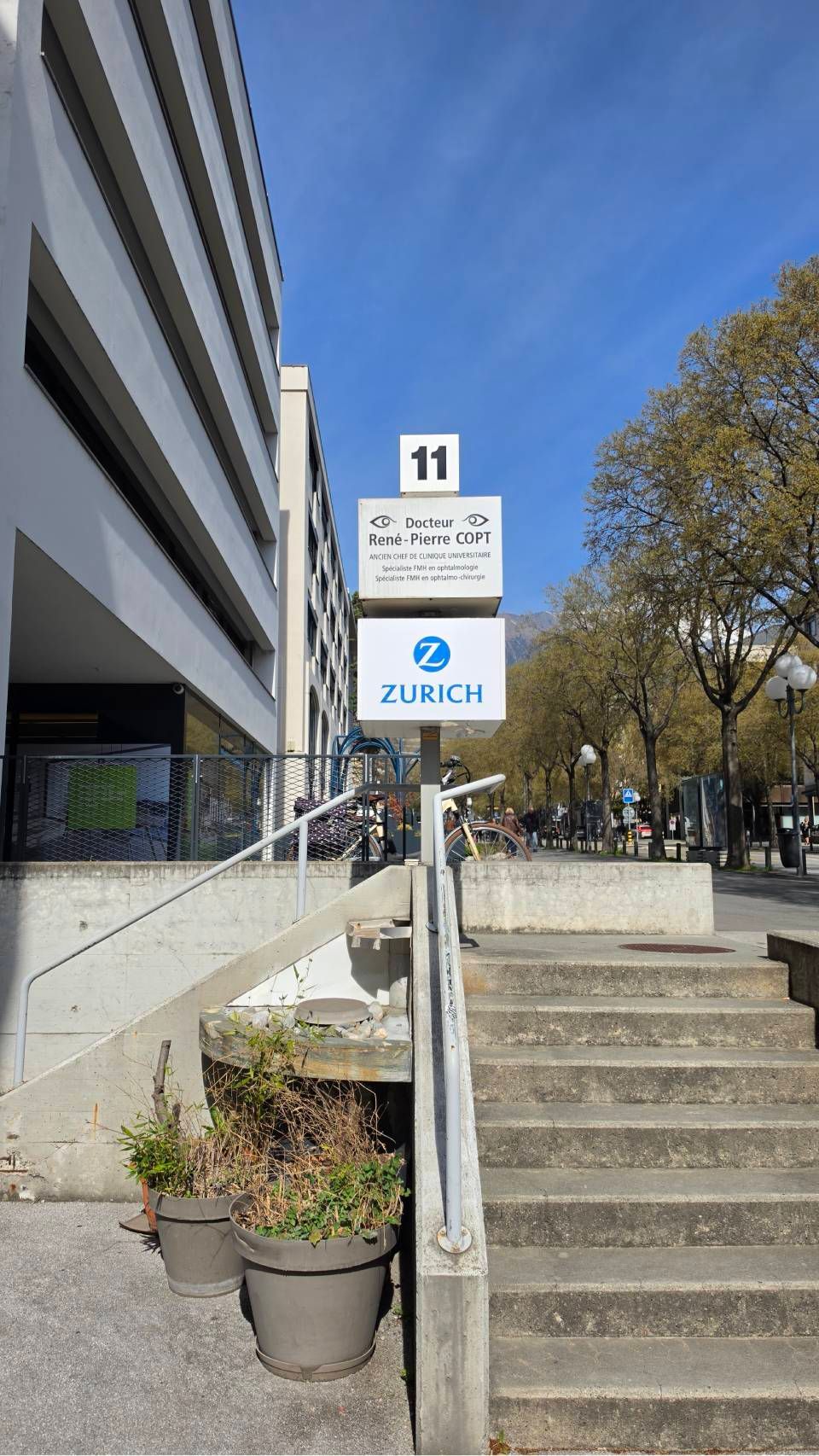 Escalier extérieur à côté d'un bâtiment moderne avec l'enseigne Zurich et des arbres en arrière-plan