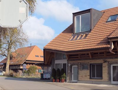 Moderne weisse Häuser mit Balkonen und umzäuntem Vorgarten in einer sonnigen Strasse
