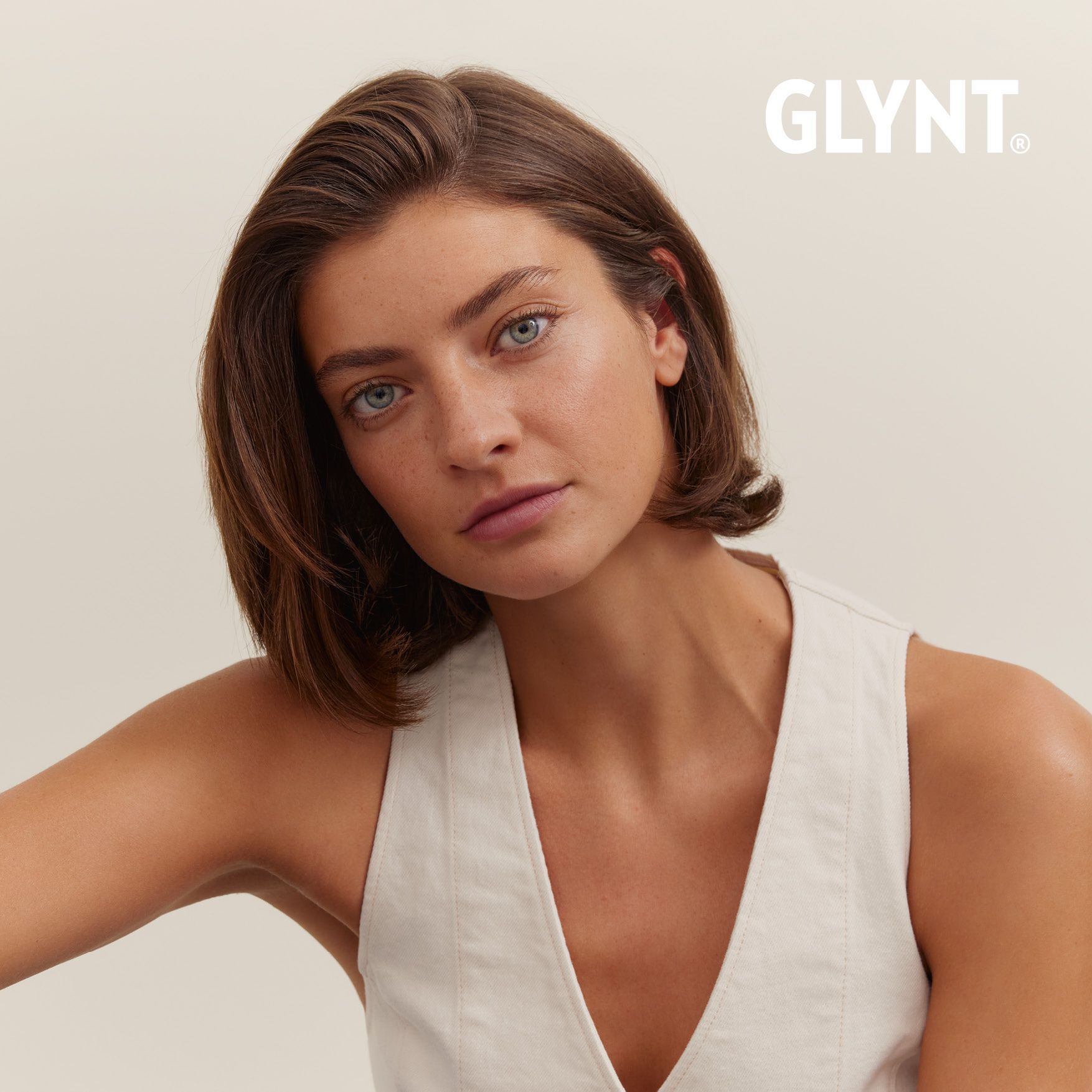 Frau mit kurzen braunen Haaren, trägt ein helles Oberteil und blickt in die Kamera.