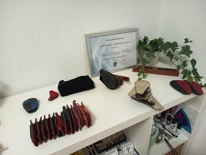 Un estante con bufandas dobladas, sombreros, zapatos, un certificado enmarcado y una planta trepadora