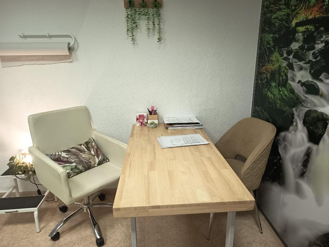 Pequeña sala de reuniones con mesa de madera, dos sillas y un mural de una cascada en la pared.