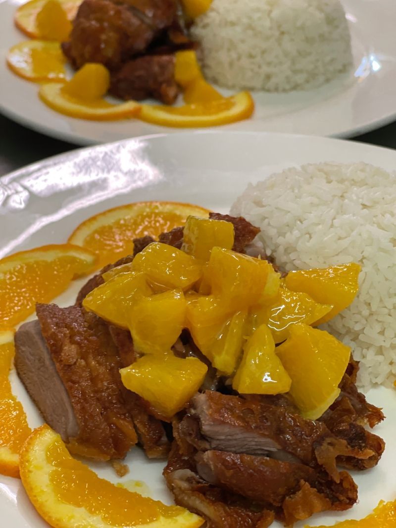 Un gros plan d'une assiette de nourriture avec du riz et des oranges sur un morceau de viande