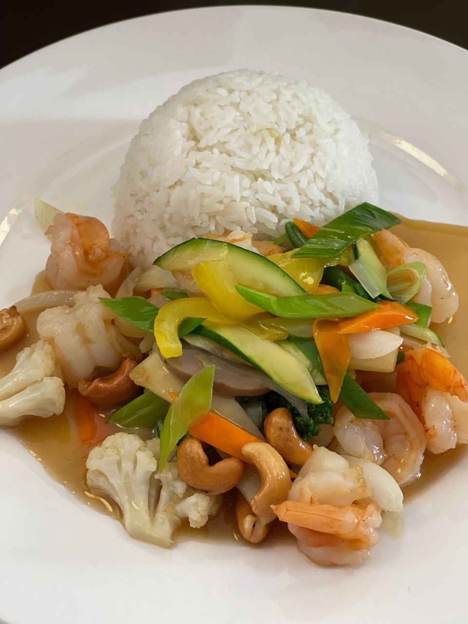 Une assiette blanche garnie de crevettes, de riz et de légumes.