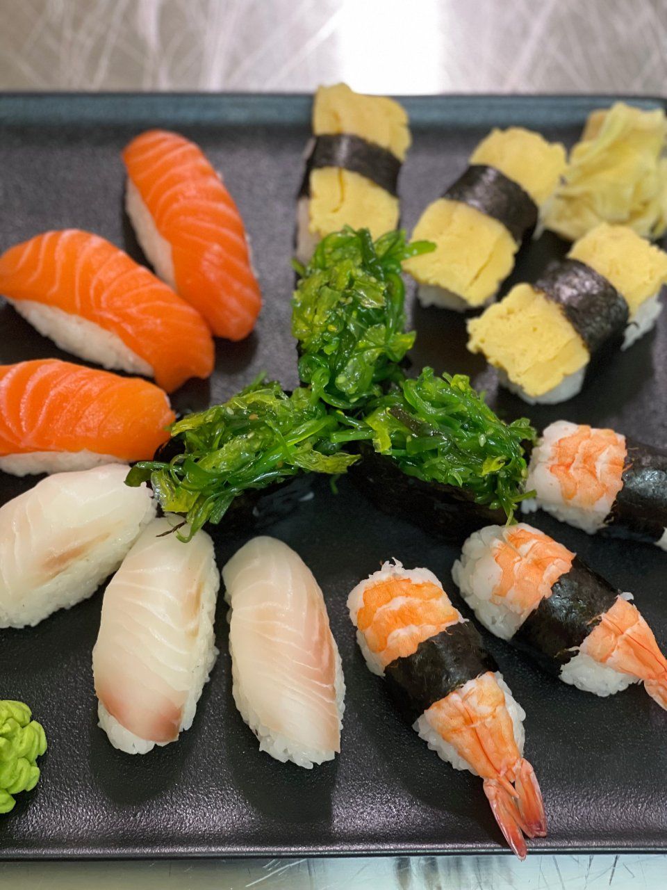 Une assiette noire garnie de différents types de sushi