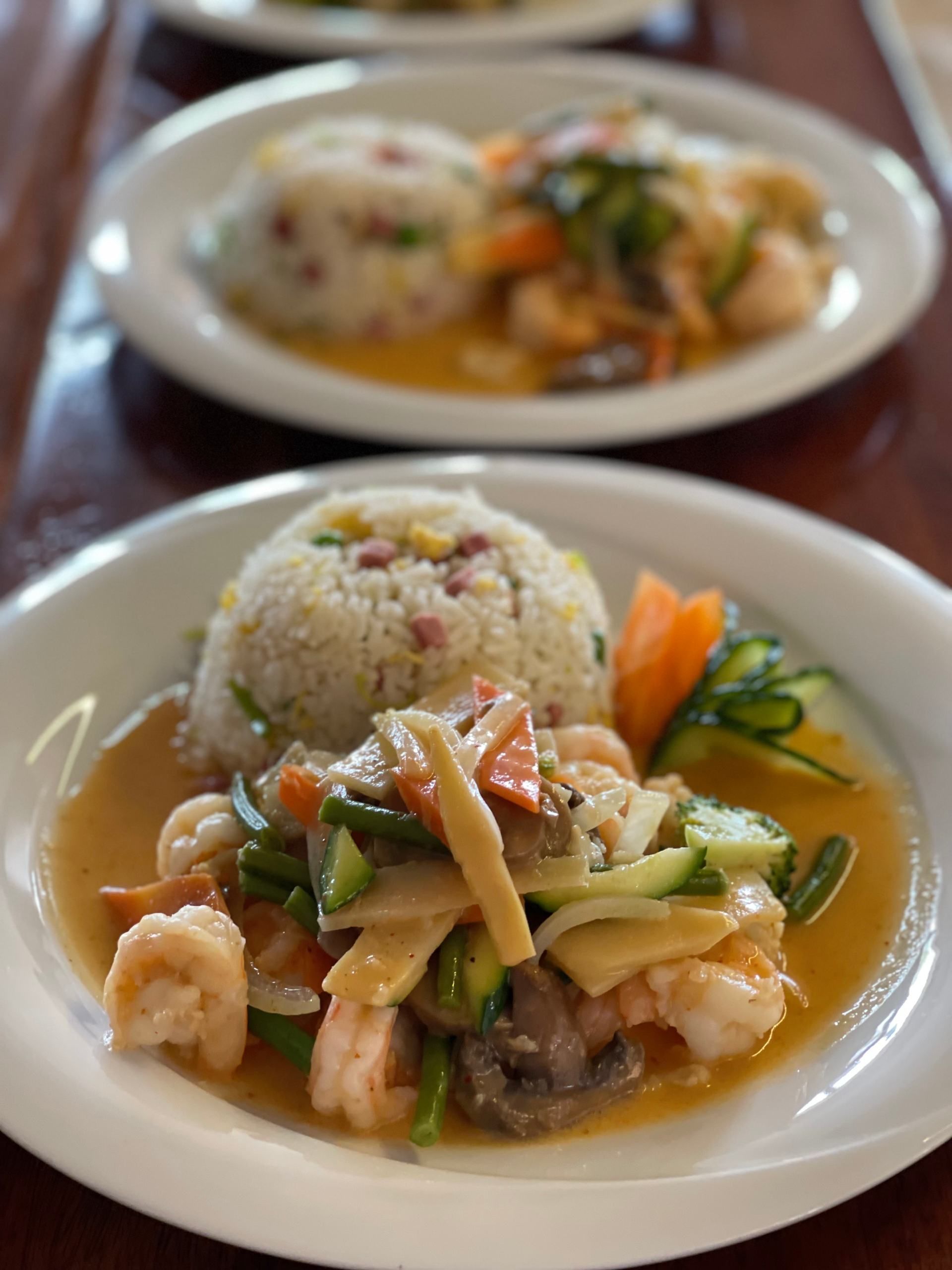 Une assiette blanche garnie de crevettes, de riz et de légumes.
