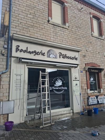 Boulangerie-pâtisserie en façade, avec porte ouverte et échelle extérieure, façade en briques et enseignes.