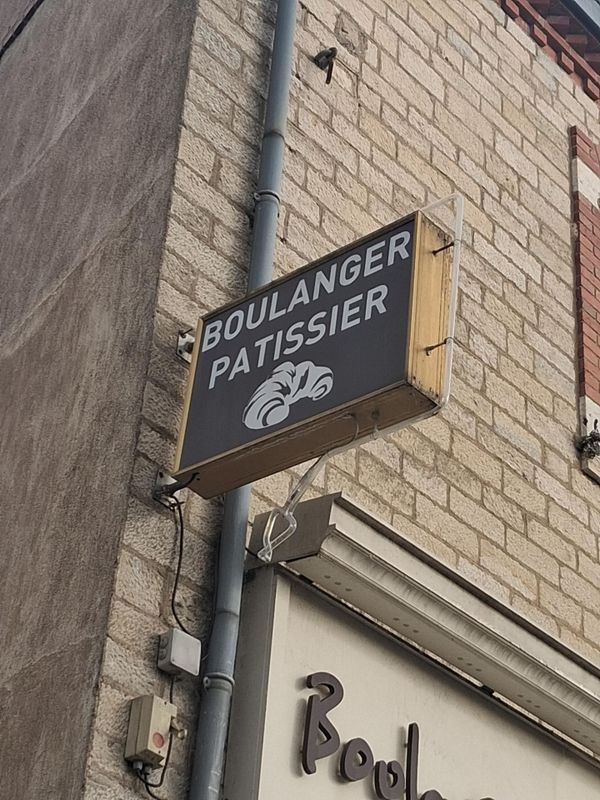 Enseigne de boulangerie indiquant BOULANGER-PÂTISSIER sur la façade d'un bâtiment en briques.