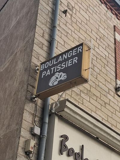 Enseigne de boulangerie indiquant BOULANGER-PÂTISSIER sur la façade d'un bâtiment en briques.
