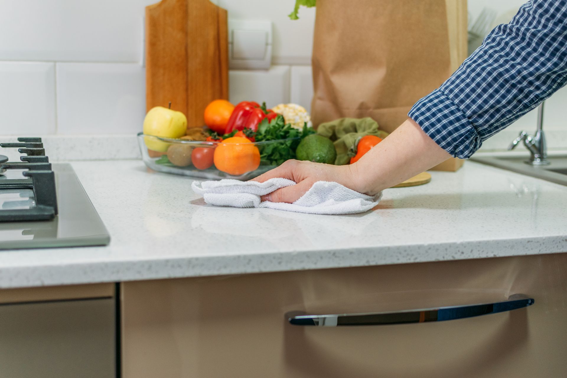 Essuyer à la main le plan de travail de la cuisine à côté de légumes frais et d'un sac en papier.
