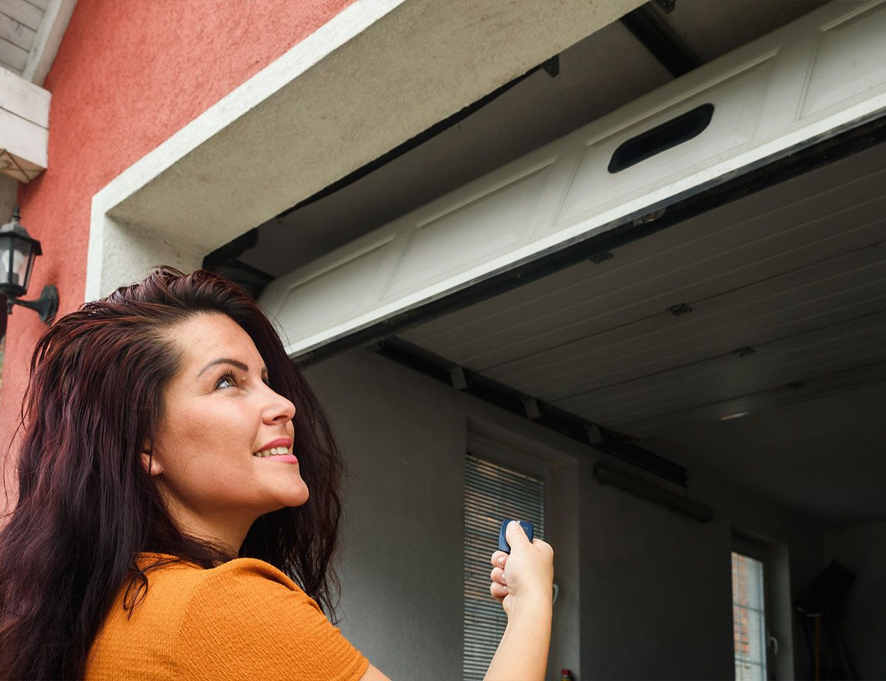 Télécommande pointée sur une porte de garage motorisée actionnée à l'aide d'une télécommande 