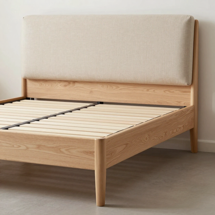 Estructura de cama de madera clara con cabecero tapizado en color beige en un dormitorio minimalista.