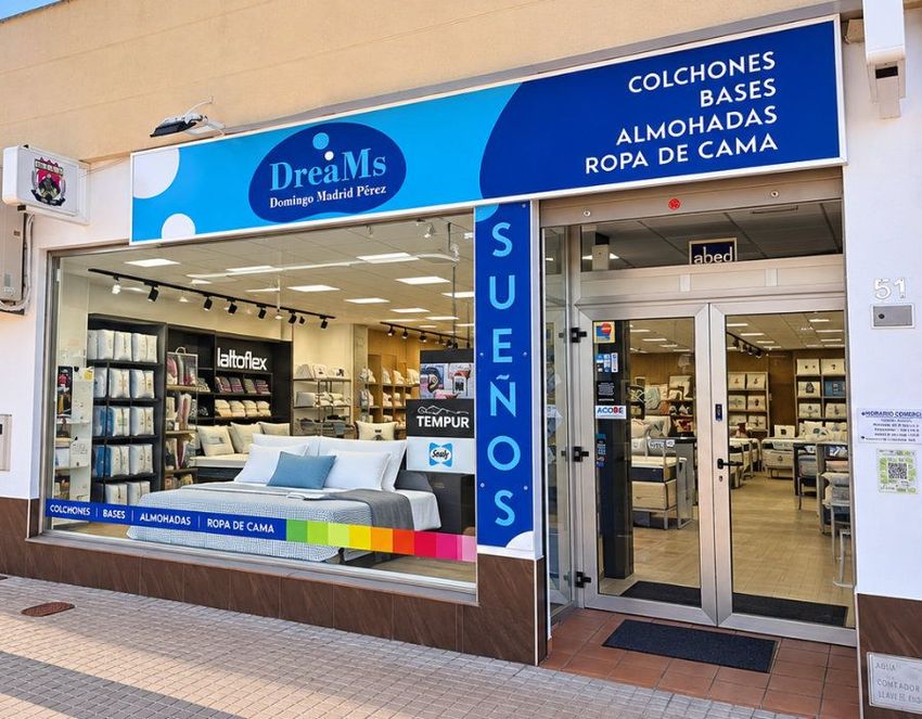 Fachada de la tienda de ropa de cama DreamS con letrero azul y exposición de colchones y sábanas.