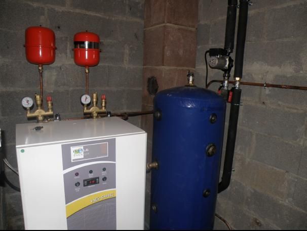 Système de chauffage avec vases d'expansion rouges, réservoir d'eau bleu et unité de commande blanche.