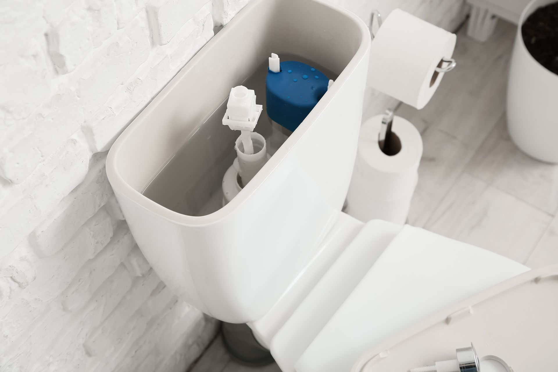 Réservoir de toilette blanc avec couvercle partiellement ouvert.