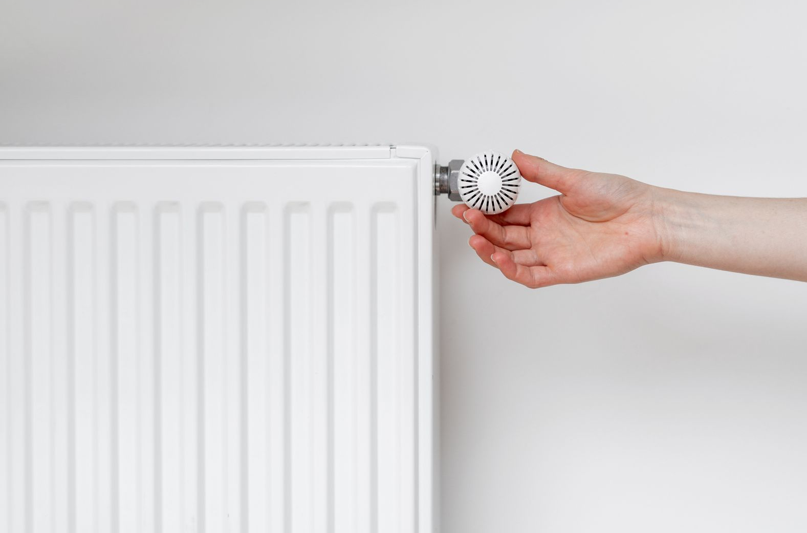 Une main ajuste un robinet de radiateur.