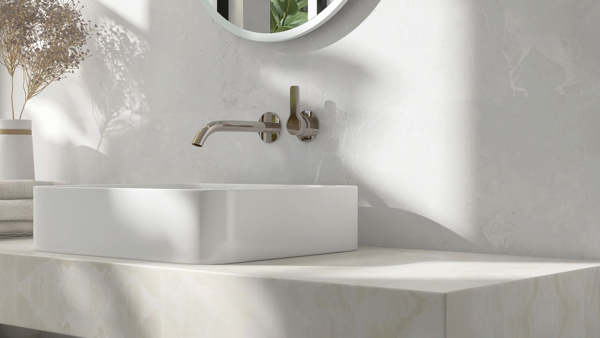 Salle de bains moderne avec lavabo rectangulaire blanc, robinet doré, miroir rond et mur blanc texturé.